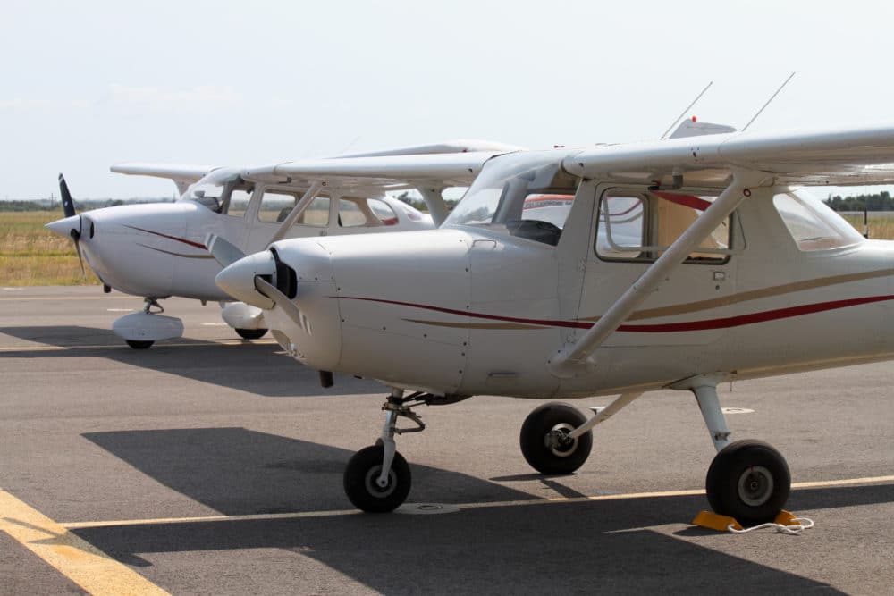 2 white and red small cessna airplane sitting on the tarmac
